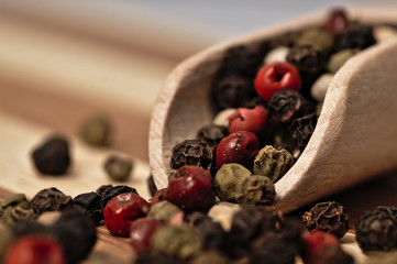 Grains of colored pepper on a wooden plank.