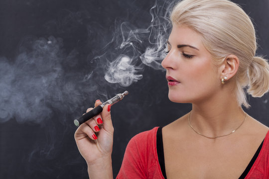 Junge attraktive blonde Frau raucht eine e-zigarette