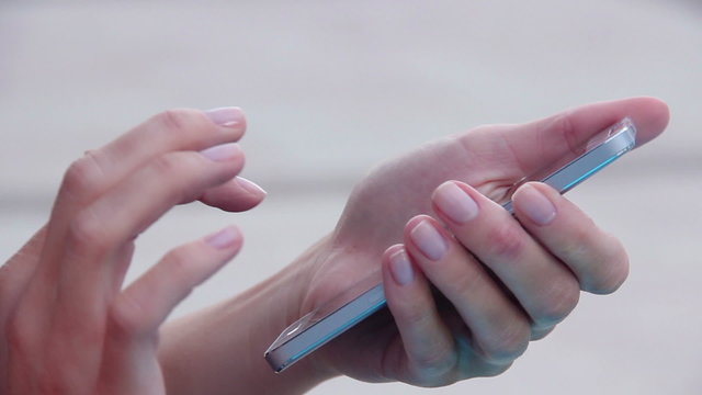 Closeup shot of female hands holding smartphone, typing text on touch screen