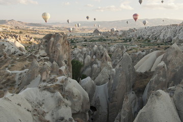 Rocky  formations in Cappadocia, Turkey with balloons on the background.