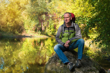 Smiling man in thought sits on a background of the  quiet river