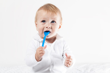 Baby hat einen blauen Löffel im Mund