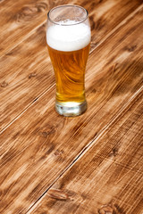 A glass of lager beer close up on wooden background brown