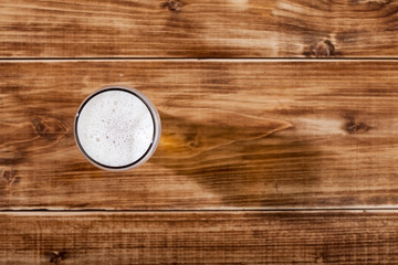 A glass of lager beer close up on wooden background brown