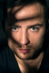 Obraz premium Young handsome man in dark shadow and ray of light