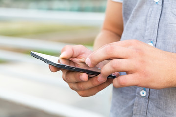 Man using his Mobile Phone outdoor, close up