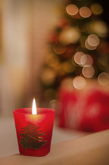 Vela de Navidad decorativa con luces desenfocadas del árbol de Navidad de fondo.