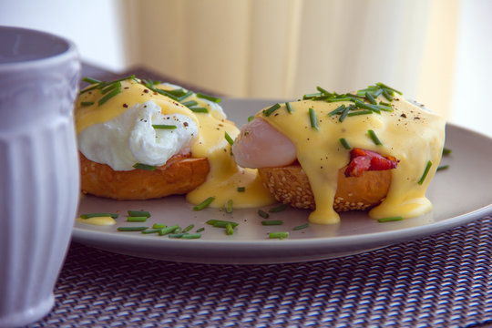 Elegant breakfast consists of eggs Benedict on a toasted bun with bacon and delicious hollandaise sauce