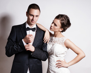 Portrait of young couple in love posing at studio dressed in classic clothes