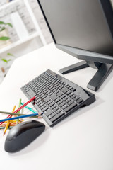 a computer with keyboard, mouse, and pencils