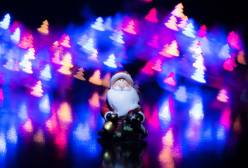 Obraz na płótnie Canvas Santa Claus on the background of colorful bokeh in the form of Christmas trees