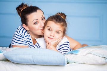 Mother and her happy daughter lying on a bed