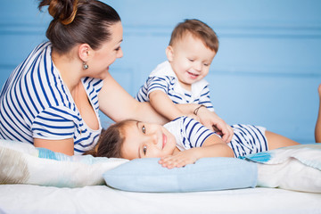 Mother and her happy children lying on a bed