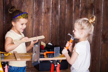 Two little girls making very interesting creations with tools and wood at home
