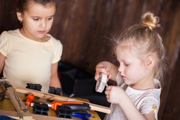 Two little girls making very interesting creations with tools and wood at home