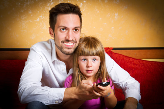 Little girl and her borther watching tv at home