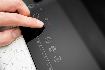 Man hand turns on modern induction cooker