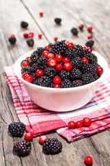 blackberries and cranberries in a bowl on wooden table