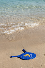Fototapeta na wymiar Racquets on a wet sandy beach with map of Greece on them.