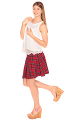 Pretty girl in a vest and skirt behind white wall