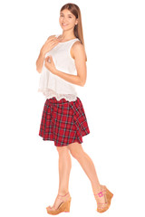 Pretty girl in a vest and skirt behind white wall