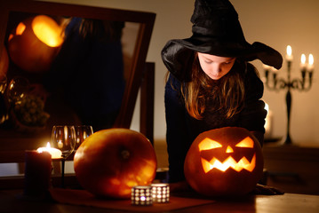 Little girl wearing halloween costume playing with a pumpkin