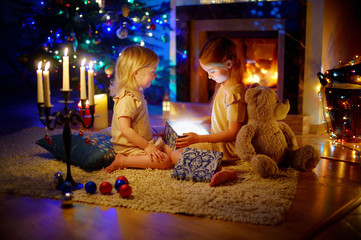 Obraz na płótnie Canvas Adorable little girls opening a magical Christmas gift
