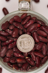 Dry red beans in a glass mug and Indian rupees.