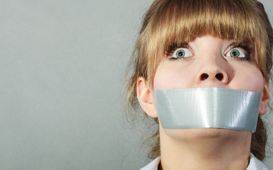 Scared woman with mouth taped shut. Censorship.