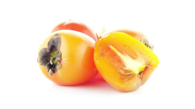 Red ripe persimmons rotating over white background.
