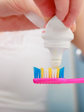 Woman hands putting toothpaste on toothbrush