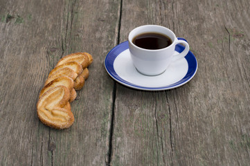 cup of coffee on a saucer with a blue border and cookies in a ro
