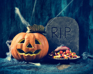 carved pumpkin, gravestone and Halloween candies