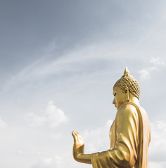 Golden buddha hand on 'O.K.' sign (peace) with blue sky and clou