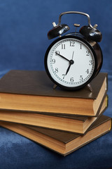 alarm clock and old books on a blue background