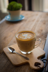 Hot art Latte Coffee in a cup on wooden table and Coffee shop bl