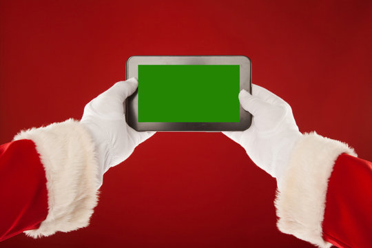 Santa Claus is holding plate with a green background. Red