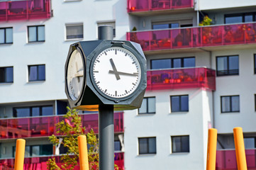 Öffentliche Uhr vor einer Wohnhausanlage