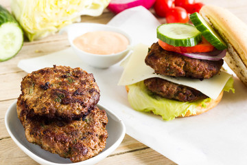 Healthy homemade hamburger with vegetables in the background.