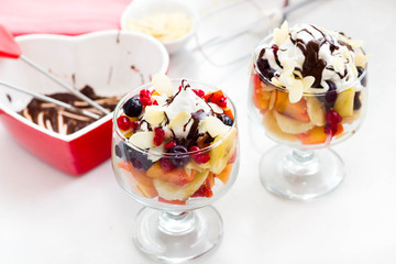 Fruit salad with whipped cream, chocolate sauce and almond slices.