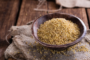 Raw Bulgur (on wooden background)