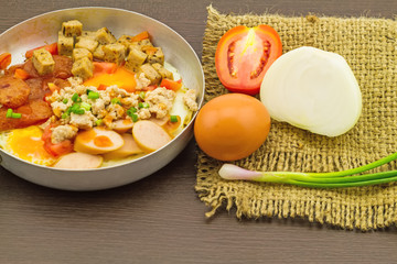 Indochina pan-fried egg with garnish (tomatoes , chili ,pepper , chili sauce , bacon , pork ,onion , ) in sack fabric on black wooden
