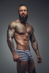Fototapeta na wymiar Brutal tattooed man in stripes panties.