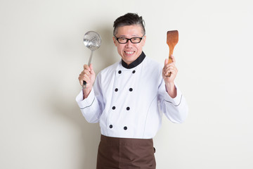 Mature Asian Chinese chef with kitchen tools