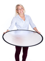 Blondes Mädchen hält einen Fotoreflektor und lächelt