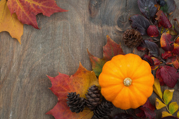 wooden background with seasonal pumpkin and leaves, top view