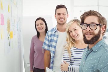 Portrait of smiling business people next to sticky notes