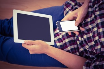 Man using smartphone while holding digital tablet