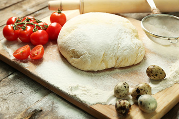 Dough on cutting board with cherry and quail eggs on table close up