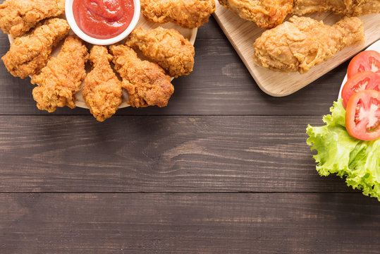 fried chicken drumstick and vegetables on wooden background